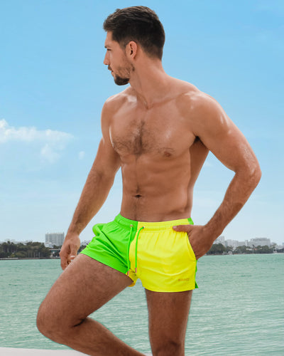 Male model overlooking the Miami skyline is wearing the SINGLE BILINGUAL (NEON YELLOW/GREEN) Show Shorts, from BANG! a men’s beachwear brand based in Miami.