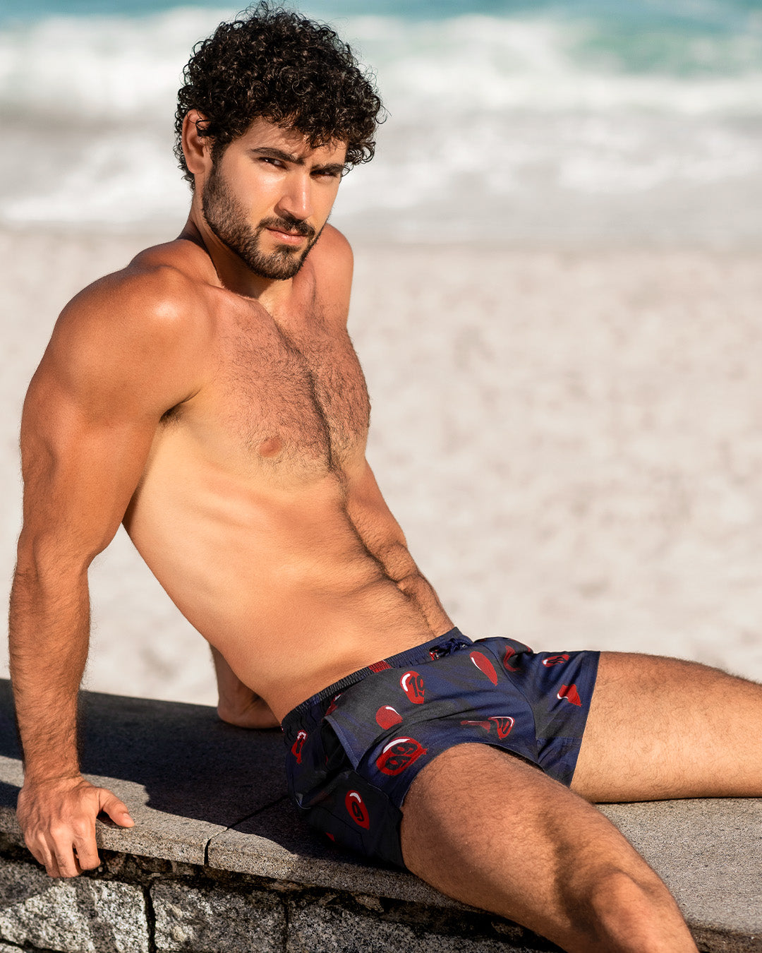 DC2 99 Red Balloons Poolside Shorts — model lounging by the beach wearing navy quick-dry shorts with red balloon print, tailored fit, and side pockets for a sleek finish.