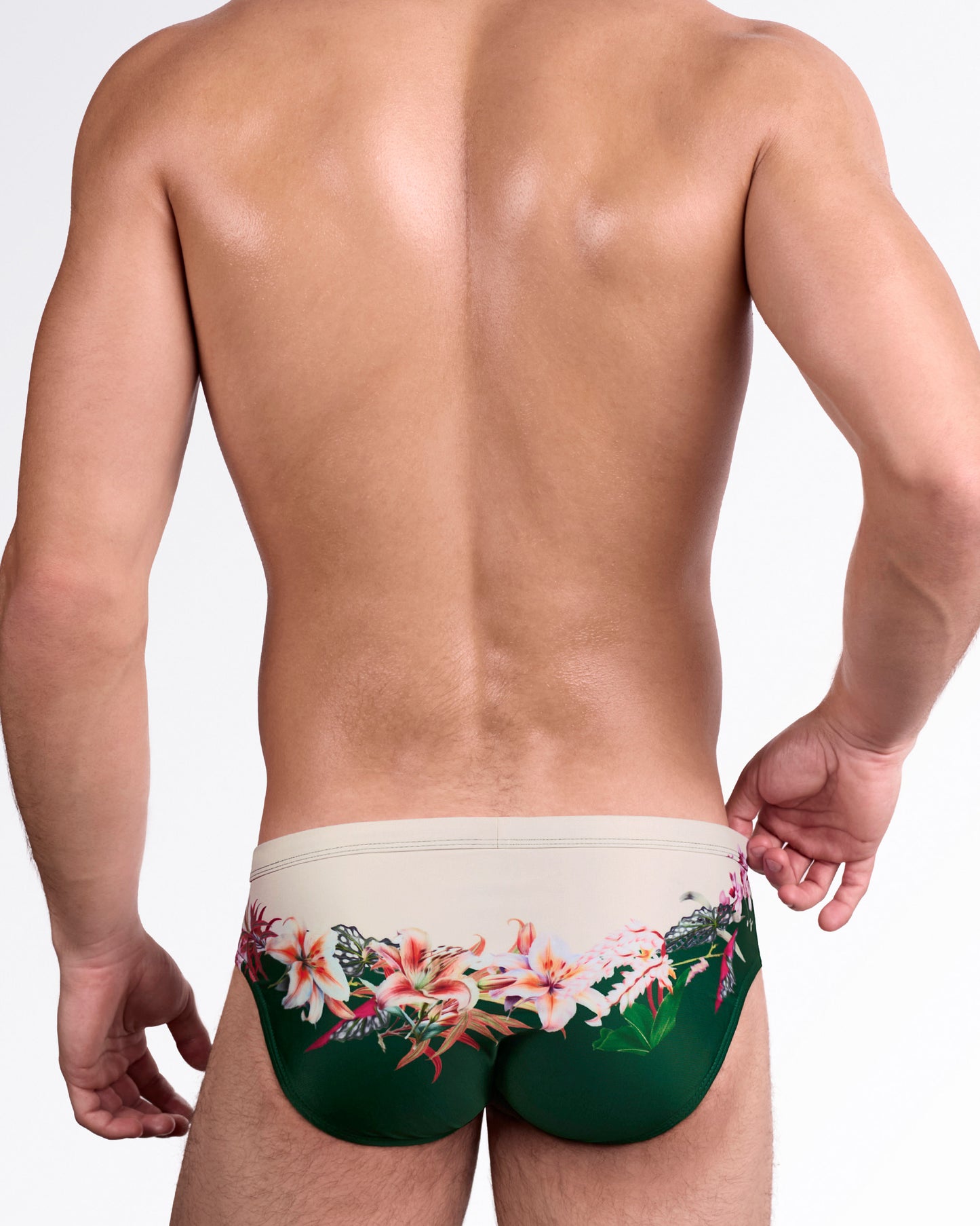 DC2 Bloom Service Swim Brief — back view showcasing wraparound botanical artwork with soft beige upper panel and rich green lower contrast.