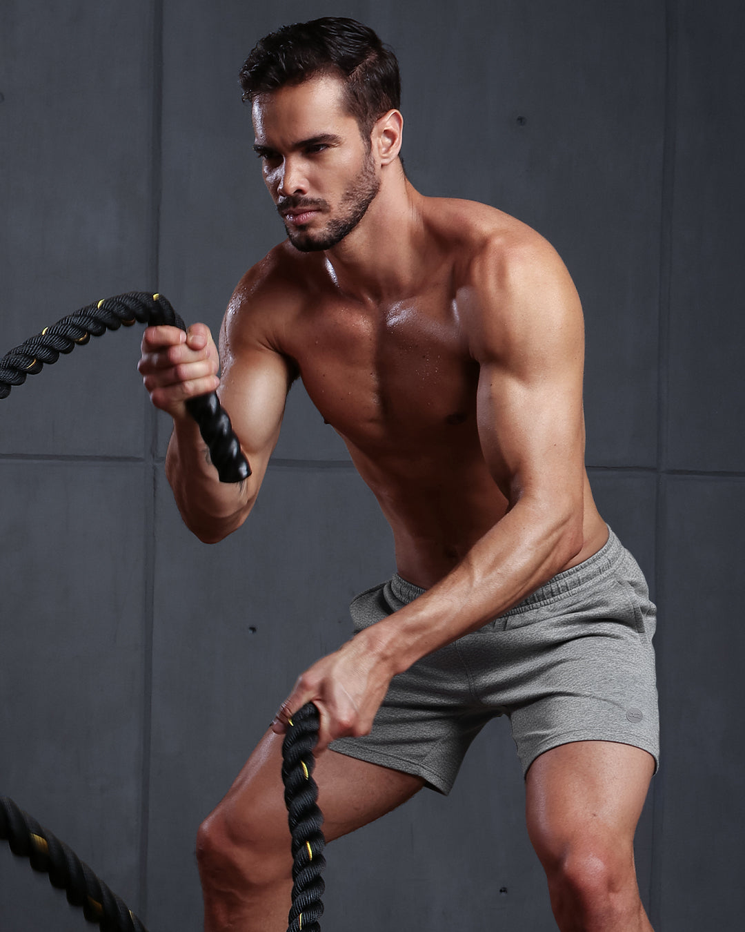 Model wearing DC2 Grey Anatomy Jogger Shorts, working out with battle ropes, showcasing the athletic fit, soft stretch fabric, and performance-ready design.
