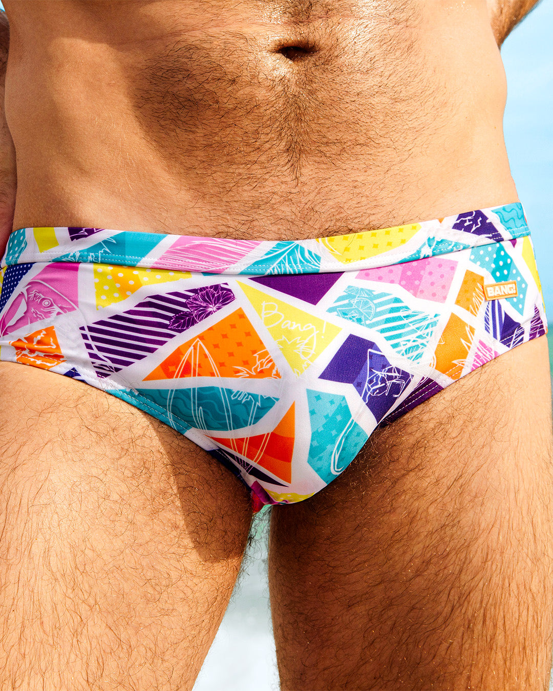 Close-up of a male model wearing MOSAIC Swim Briefs by BANG! Clothing, featuring a vibrant multicolored geometric print. These stylish men's swim briefs are designed for summer beachwear and poolside fashion.