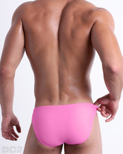 Back view of a male model wearing men’s PINKTYQUE swim mini-brief in light rose pink by the DC2 a BANG! Clothes brand for men's beachwear.