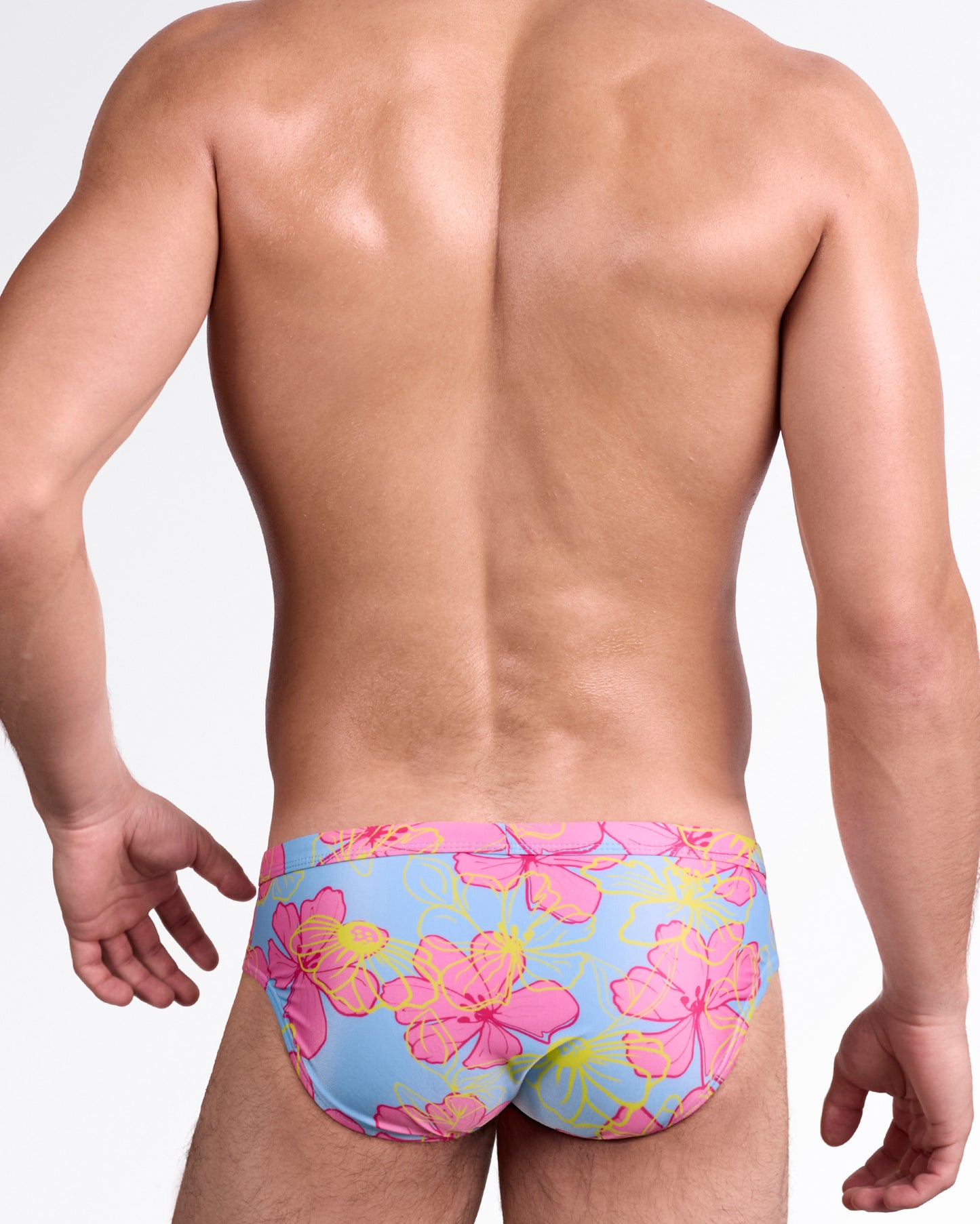 BANG Surf Flowers Pink Blue Swim Brief — back view highlighting full-coverage rear with bold tropical flower pattern in pink and yellow over blue background.