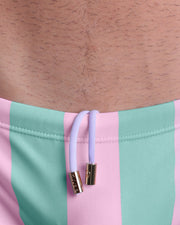 Close-up view of the THE KEN (MALIBU EDITION) Swim Sunga mens swimsuit with an internal drawstring cord in white showing custom branded golden buttons by BANG! clothing brand.