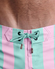 Close-up view of men’s summer Flex shorts by BANG! clothing brand, showing aqua-green color cord with custom-branded golden cord ends, and matching custom eyelet trims in gold.