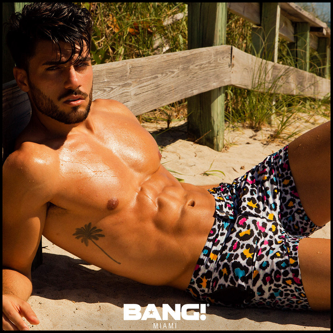 Sexy male model on the beach wearing new BANG Clothes Miami premium 8-bit pop leopard beach shorts upgrade your swimwear gay designer quality
