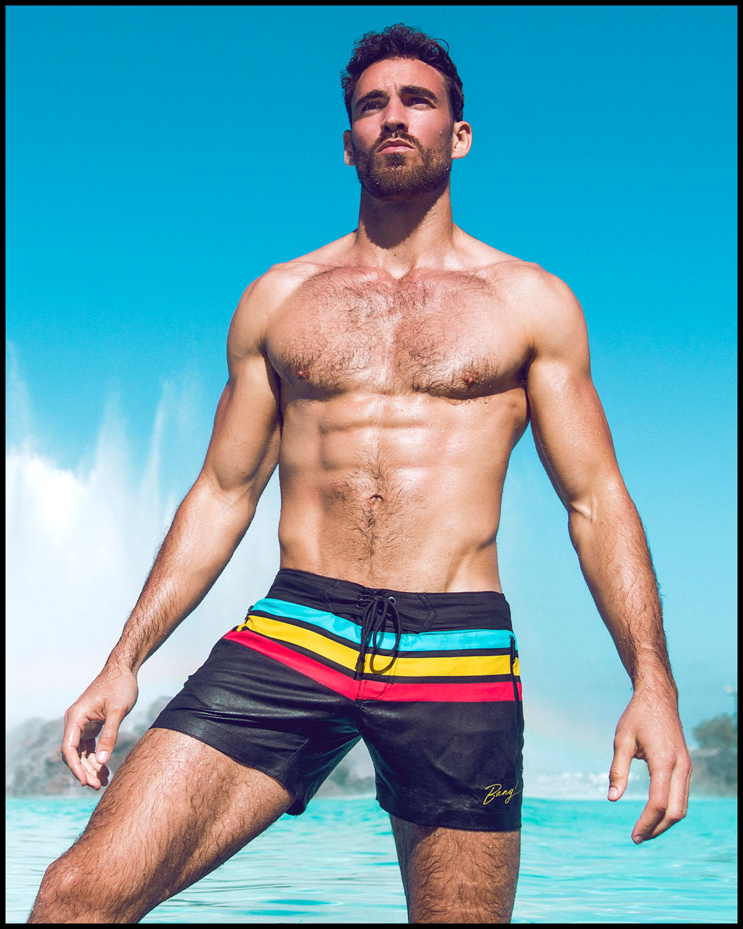 Front view of a sexy male model wearing BANG Miami flex shorts Bionic Stripes series black blue yellow red 2021 lgbtq nation