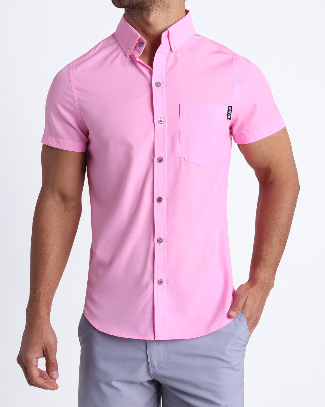 Front view of a sexy male model wearing LA BEACH EN ROSE mens short-sleeve stretch shirt in light pink by the Bang! brand of men's beachwear from Miami.