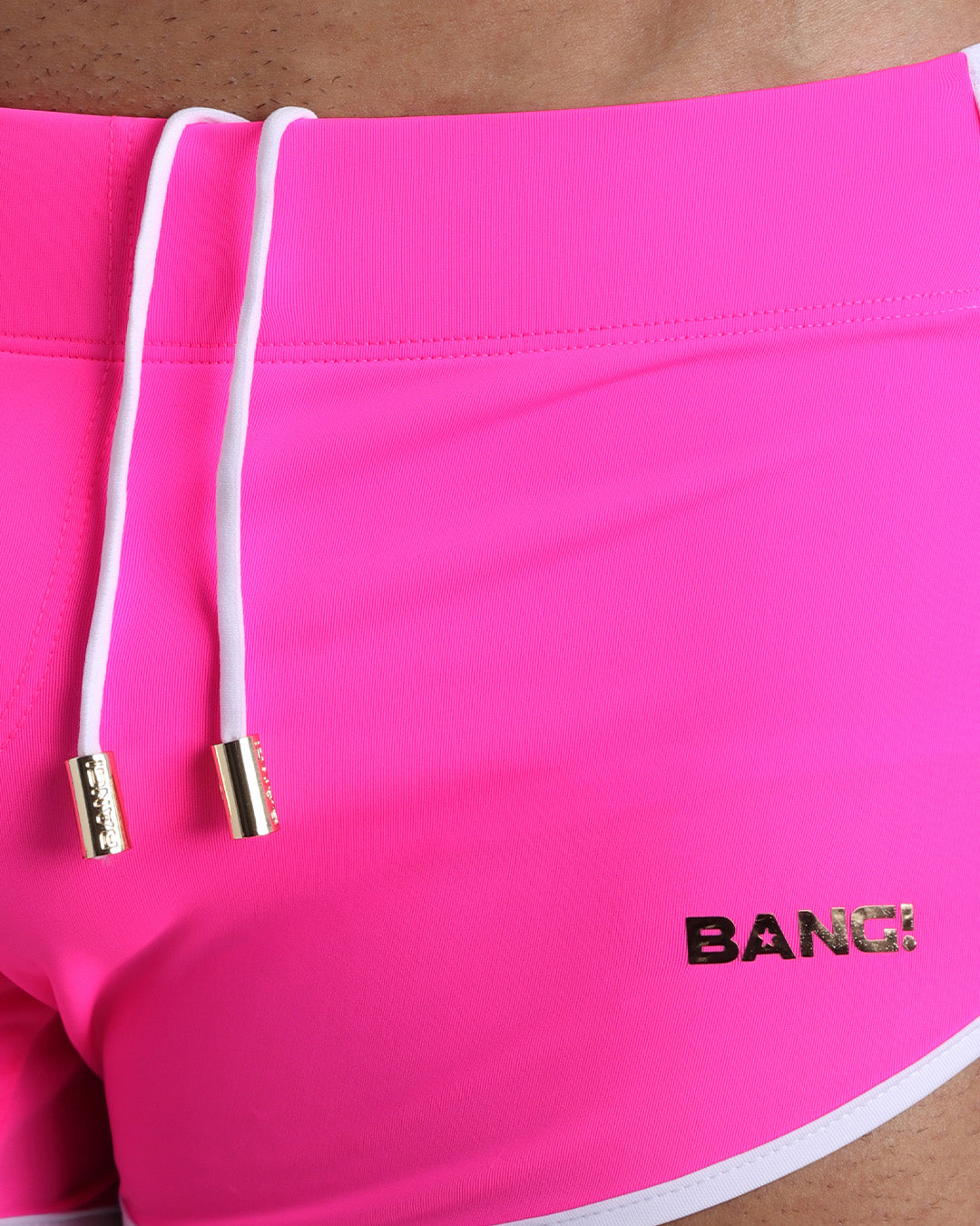 Close-up view of men’s summer beach shorts by BANG! clothing brand, showing white cord with custom branded golden cord ends, and matching custom eyelet trims in gold.