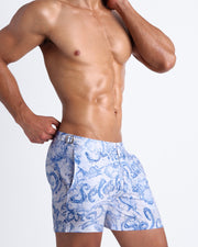 Left side view of men’s shorter leg length shorts in blue and white water strokes made by Miami based Bang brand of men's beachwear