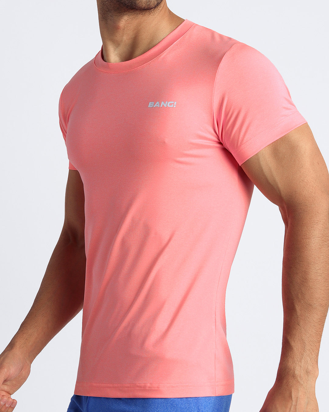 Side view of men’s exercise tee in a orange pink color made by BANG! Clothing the official brand of mens beachwear.