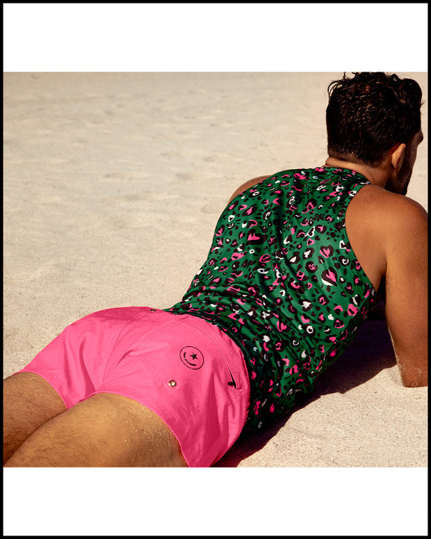 Male model laying down at the beach wearing the CAMO CHAMELEON quick-dry ultra soft Tank Top and the PINK BOMB Mini Shorts by BANG! Clothes the official brand of men’s beachwear.