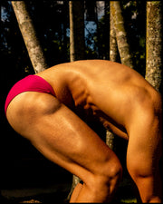 Male model wearing the CONFESS MAGENTA Swim Brief a bright magenta pink color. The swimsuit is by BANG! Clothes, the official brand of men’s high-quality beachwear.