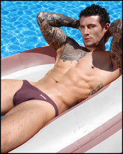 Male model in a pool wearing the BUST A MAUVE Swim Mini Brief by BANG! Clothes is the official brand of men’s swimwear brand based in Miami, FL.