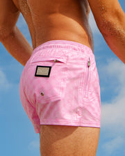 A man wearing light pink MONO PINK Poolside Shorts by DC2, a Miami-based brand. The shorts feature a stylish DC2 monogram print.