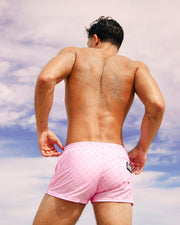 Male model wearing the PADAM PINK Poolside Shorts. The signature monogram print of the DC2 men's swimwear brand by Bang Miami menswear clothing.