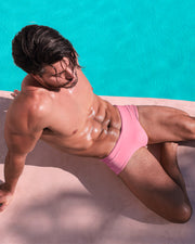 Male model by the pool wearing the Whispering Rosé Swim Sunga for Spring/Summer 2024 from the new DC2 capsule brand by BANG! Miami swimwear.
