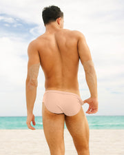 Image of a male model wearing the SKINNY DIP men's Swim Brief in beige fair light pink color by DC2 Miami beachwear by BANG! Miami swimwear.