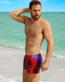 Male model at the beach in Miami, FL wearing the CONFESSIONS ON A SAND FLR VOL 2 Show Shorts by BANG! Clothes, a men’s beachwear brand.