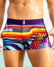 Close-up of the POOL POSITION swim trunks by BANG! Clothing, featuring a vibrant, multicolored design with side zippered pockets and a double-button waistband for added style and functionality.