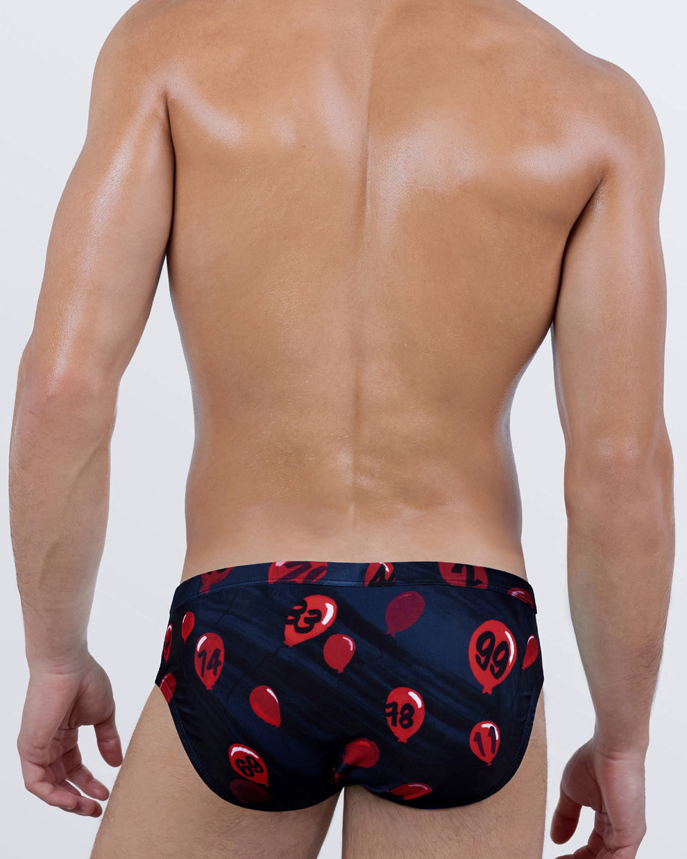 Back view of 99 Red Balloons Swim Briefs by BANG! – bold and playful red balloon graphics over a deep navy background, sculpted to fit.