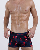 Front view of the 99 RED BALLOONS Swim Trunks – dark navy base with red balloon print featuring bold black numbers, styled in a square-cut silhouette.