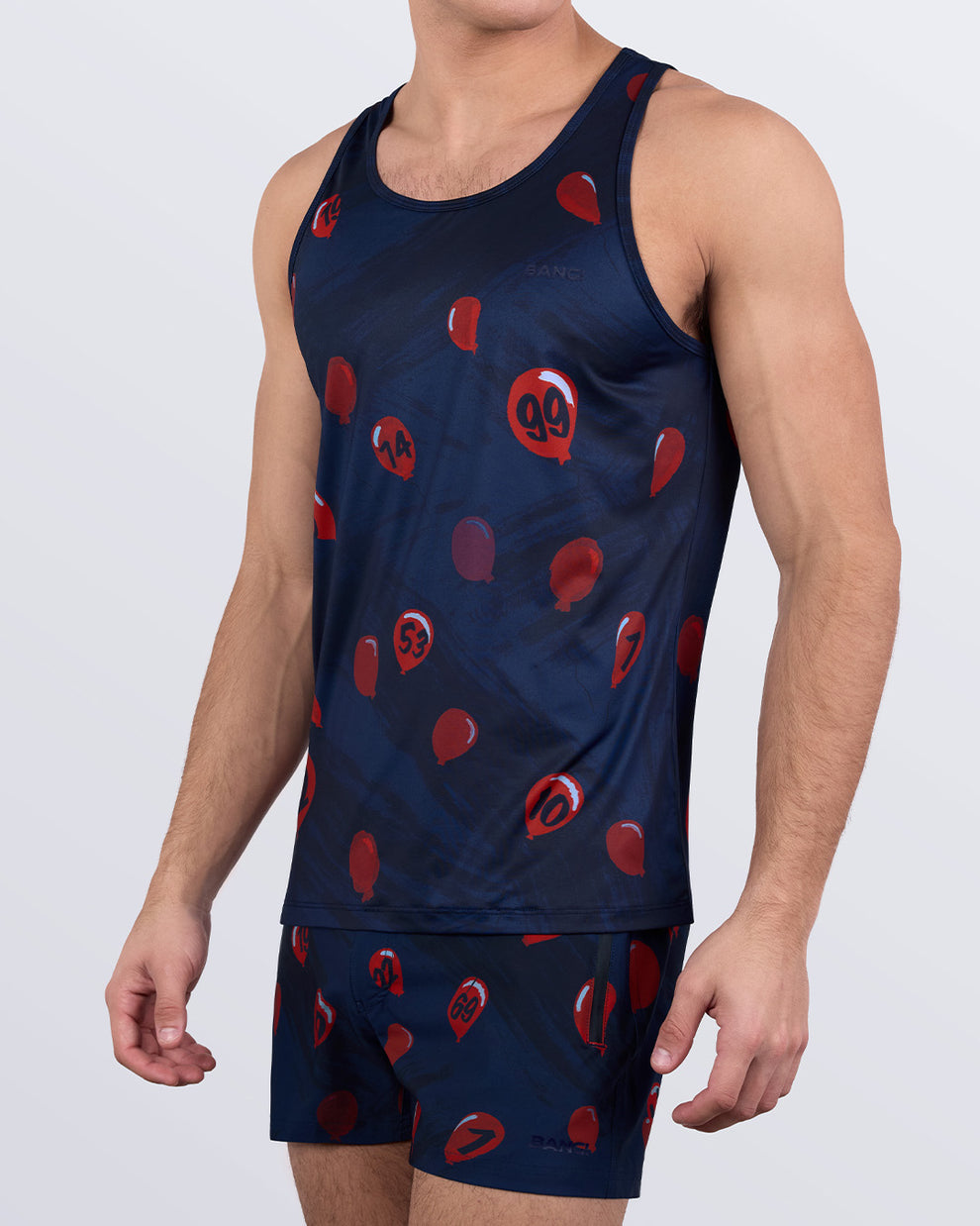 Model wearing 99 RED BALLOONS tank top and shorts set, holding red balloons – fun and festive men’s activewear outfit by BANG!® Miami