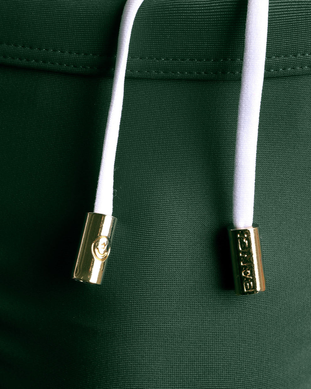 Close-up view of men’s summer swimwear Made with Italian Recycled Nylon Vita by Carvico Econyl by BANG! clothing brand, showing white cord with custom branded golden cord ends, and matching custom eyelet trims in gold.