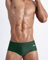 Frontal view of a sexy male model wearing men’s swimsuit made with Italian-made Vita By Carvico Econyl Nylon in dark green color by the Bang! Menswear brand from Miami.