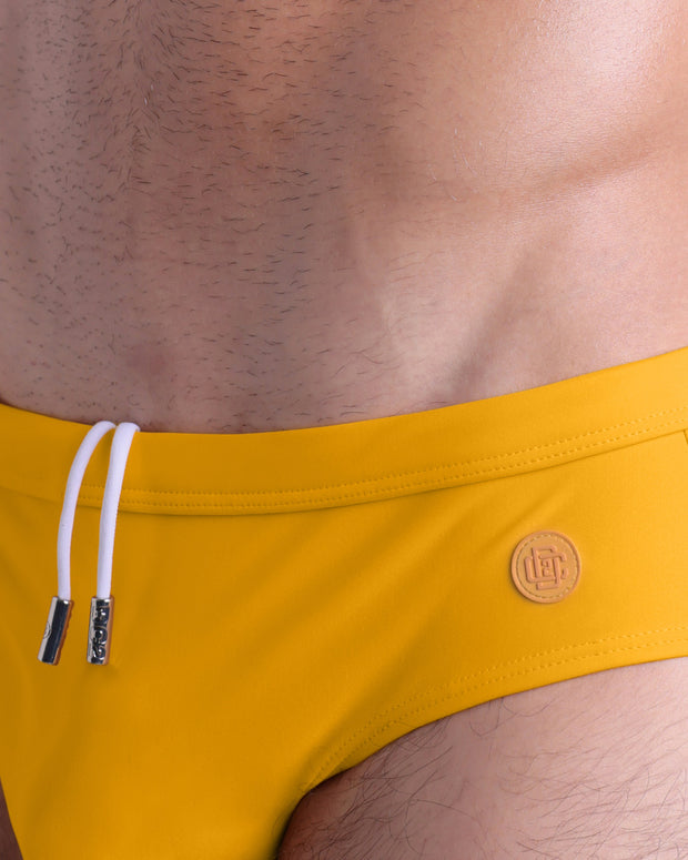 Close-up view of the AMBER SAND men’s drawstring briefs showing white cord with custom branded metallic silver cord ends, and matching custom eyelet trims in silver.