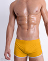 Front view of model wearing the AMBER SAND men’s swimming bottoms in a solid dark sunny yellow color by DC2, a men's beachwear brand from Miami.