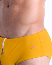 Close-up view of the AMBER SAND men’s drawstring briefs showing white cord with custom branded metallic silver cord ends, and matching custom eyelet trims in silver.