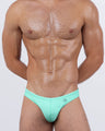 Model wearing AQUA LITE swim mini briefs for men in a smooth, solid seafoam mint color. Sleek and modern men’s swimwear with a minimal silhouette that celebrates clean lines and understated summer freshness.