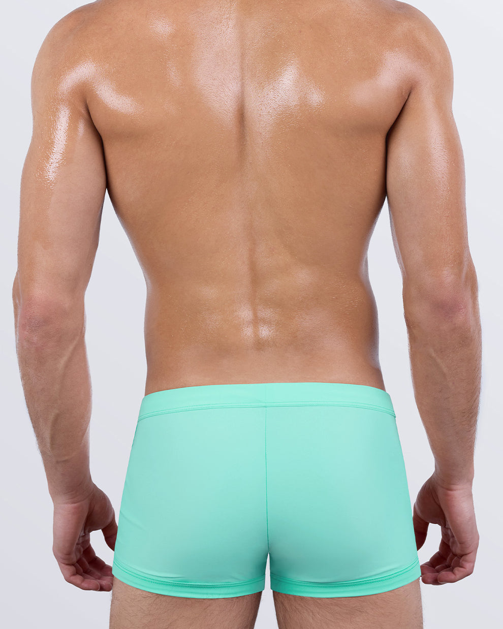 Back view of AQUA LITE men’s swim trunks in a bold pastel aqua shade. Showcases the snug, skin-hugging fit that defines the glutes with clean lines and a secure waistband, ideal for beach days or resort lounging.