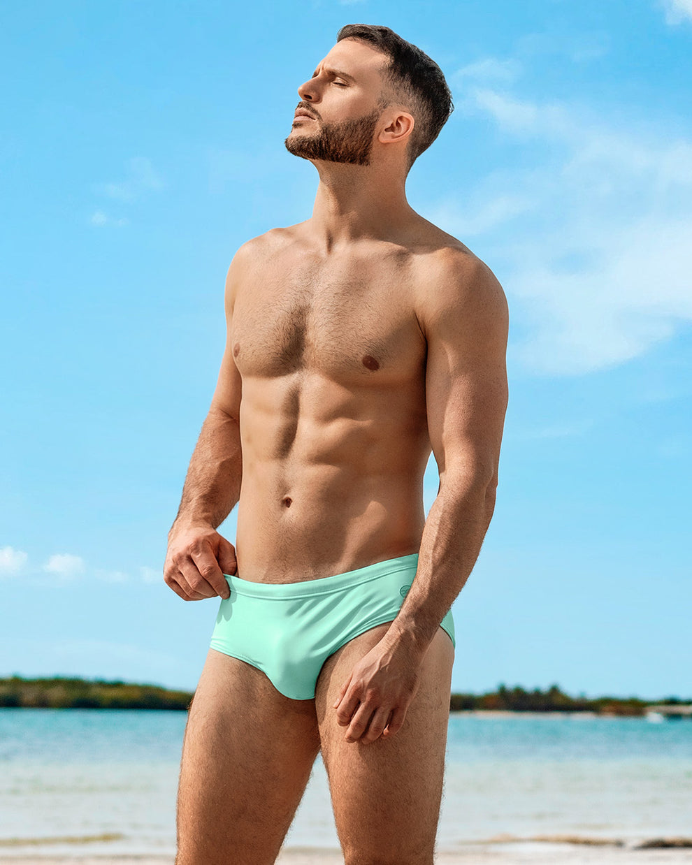 DC2 Miami Aqua Lite Swim Sunga in mint green, modeled at the beach under clear blue skies.