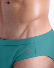 Close-up view of the ATLANTIS TEAL men’s drawstring briefs showing white cord with custom branded metallic silver cord ends, and matching custom eyelet trims in silver.