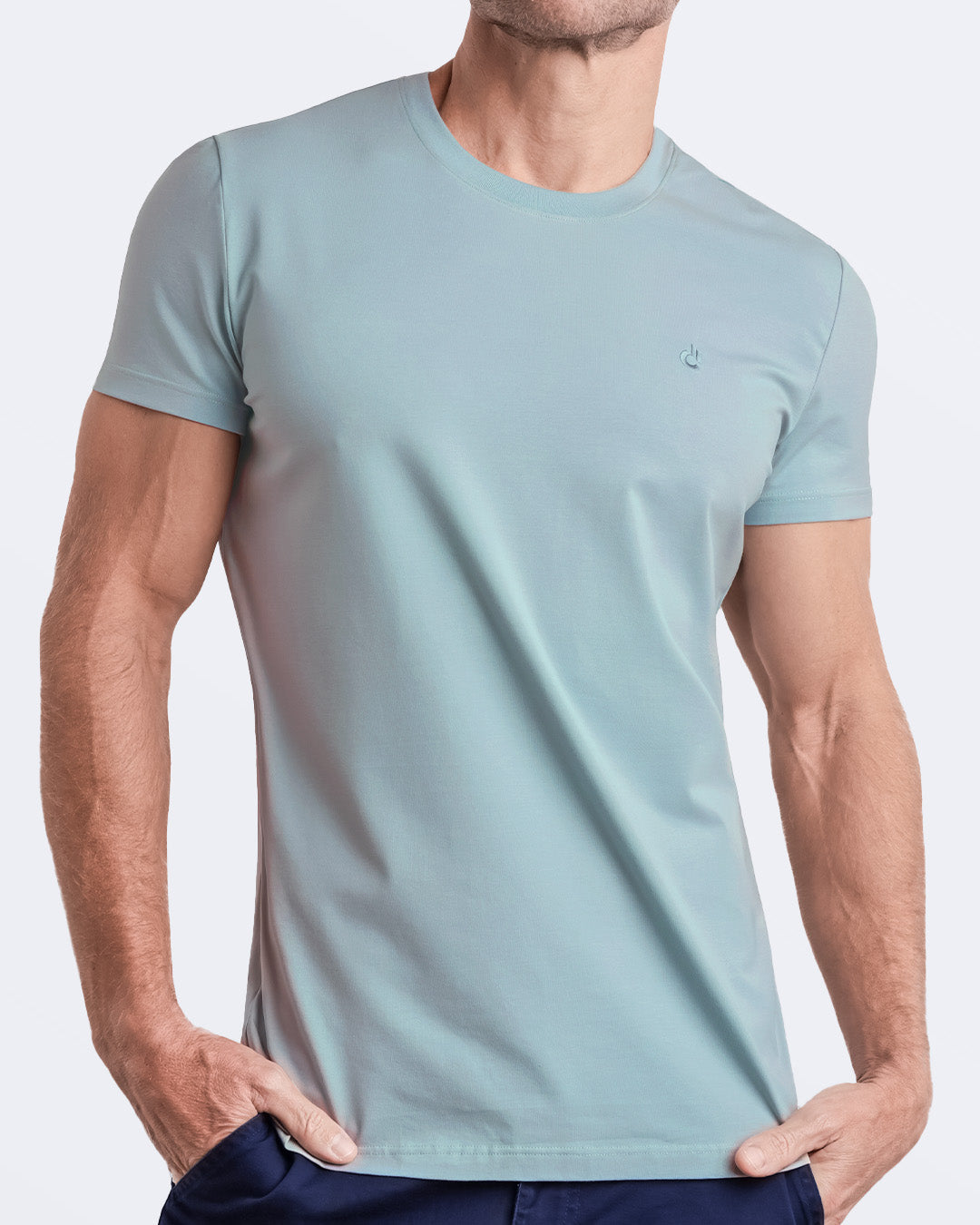 A model adjusting a light green teal modal cotton t-shirt, showcasing the breathable, lightweight fabric ideal for summer beachwear and street style. Part of the DC2 Miami men's casual collection, featuring a perfect fit for active wear