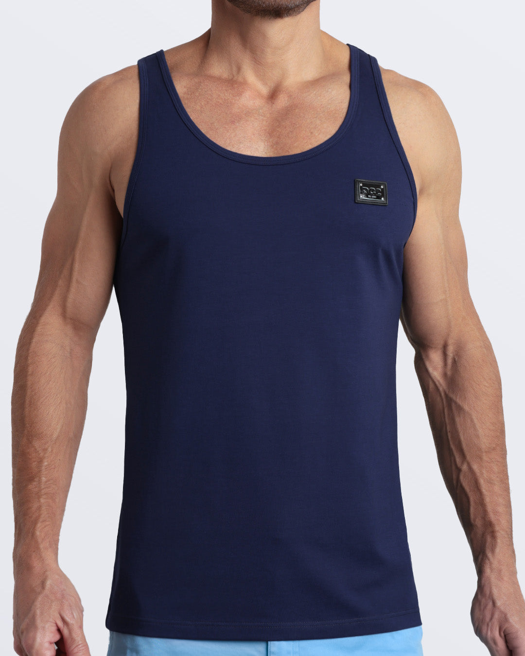 Frontal view of male model wearing the BE MY NAVY in a solid dark royal blue color casual gym tank top for men by the DC2 brand of men's beachwear from Miami.