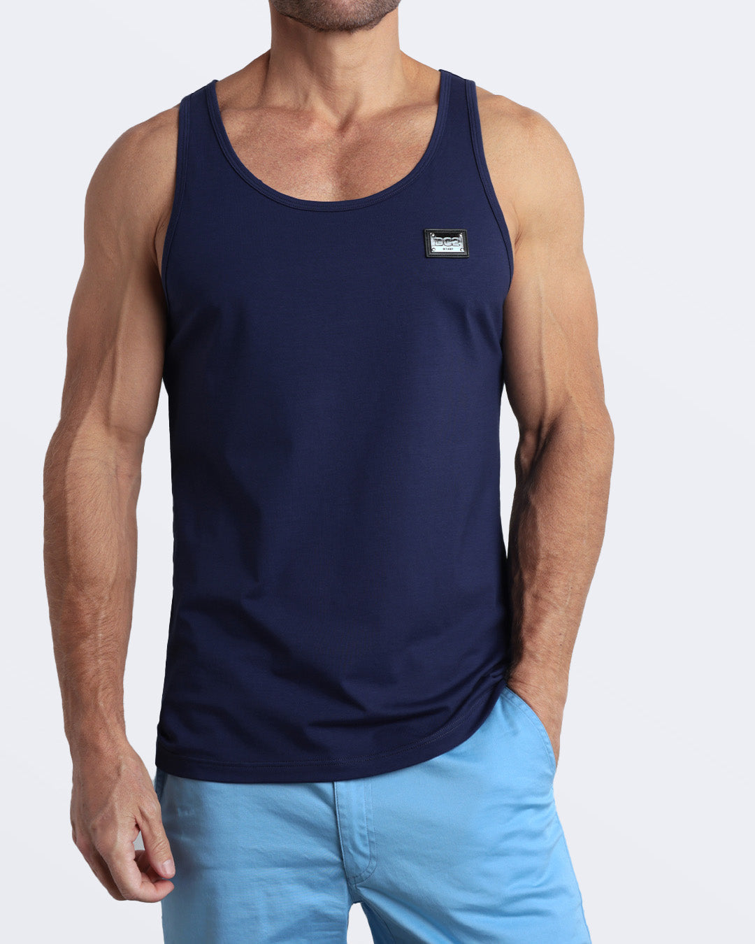 A model wearing the BE MY NAVY men's fitness breathable tank top with the BREEZY BLUE Street Shorts. The casual beach tank top is made of modal cotton blend in a solid dark blue color by DC2 Miami menswear.