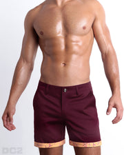 Front view of a male model wearing BEAU BERRY men's chino shorts in a solid dark red color with reversible cuff that reveals DC2® signature print when flipped out. Designed by DC2 a BANG! Miami Clothes capsule brand.