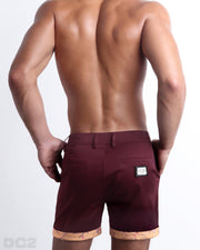 Back view of a model wearing woven twill cotton chino shorts in a burgundy red color for men. These premium quality swimwear bottoms are DC2 by BANG! Clothes, a men’s beachwear brand from Miami.