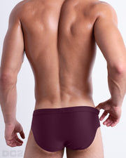Back view of male model wearing the BERRY GOOD beach briefs for men by BANG! Miami in a solid dark wine red color.