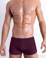 Front view of model wearing the BERRY GOOD men’s swimming bottoms in a solid dark berry color by DC2, a men's beachwear brand from Miami.