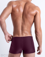 Back view of a male model wearing the BERRY GOOD men’s swim trunks by BANG! Miami in a solid wine red color.