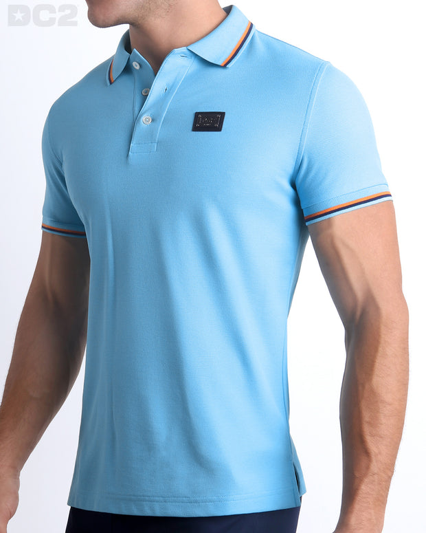 Male model wearing a slim-fitting, BISCAYNE LIGHT BLUE Pima Cotton Polo Shirt by Miami-based DC2. Solid light blue with orange and dark blue stripes on ribbed-knit collar and cuffs.