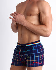 Side view of men’s BJORN THIS WAY (DARK) shorter leg length shorts in navy blue with multi color stripes in red and navy blue made by Miami based Bang brand of men's beachwear.