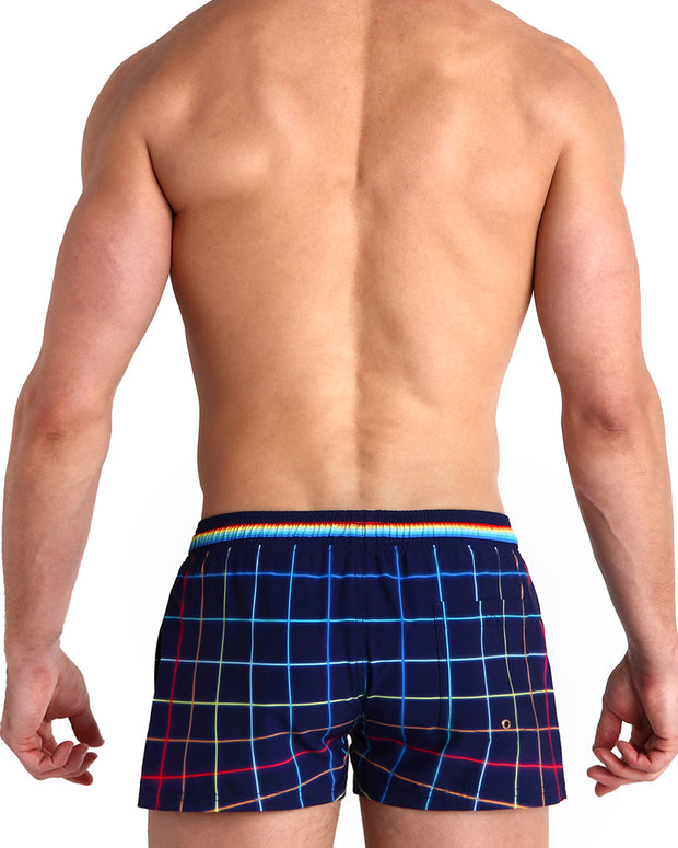 Back view of male model wearing the BJORN THIS WAY (DARK) beach trunks in navy with rainbow color stripes inspired iconic P.L. Rolando&