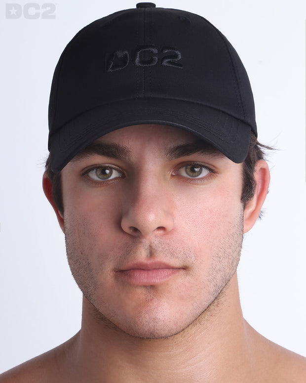 A man wearing the BLACK - Chillax Cap, a stylish black color baseball cap made from breathable fabric. The cap features a 3D raised embroidery logo on front and a curved brim for sun protection.