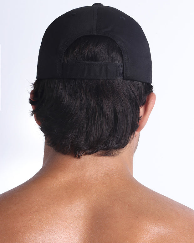 The BLACK Chillax Cap, modeled here, is in black. Its adjustable velcro strap at the back ensures a perfect fit for any head size.