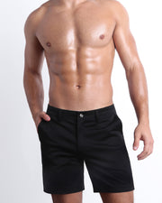 Front view of a male model wearing BLACK FOR GOOD men's chino shorts in a solid black color with reversible cuffs by DC2 a BANG! Miami Clothes capsule brand.